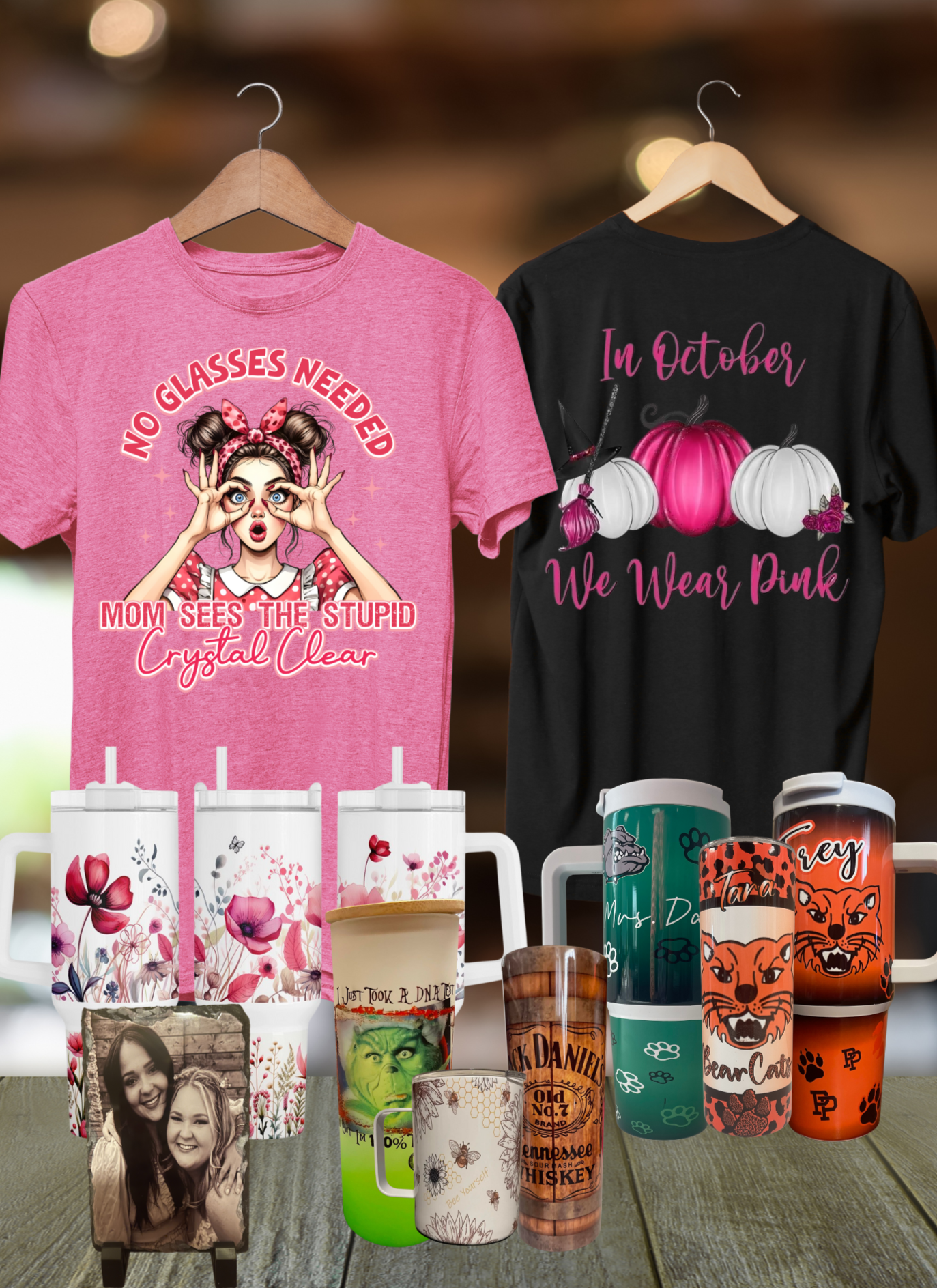 Collection of t-shirts and mugs with various designs on a wooden surface.